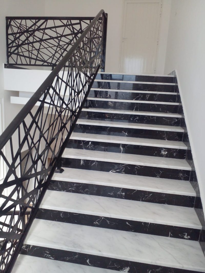 Marble staircase with black and white treads and a decorative wrought-iron balustrade in an Al Ain villa