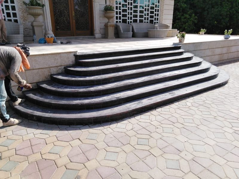 Dark stone step treads being laid over a curved entrance stair — Reef Al Ghadeer, Al Ain