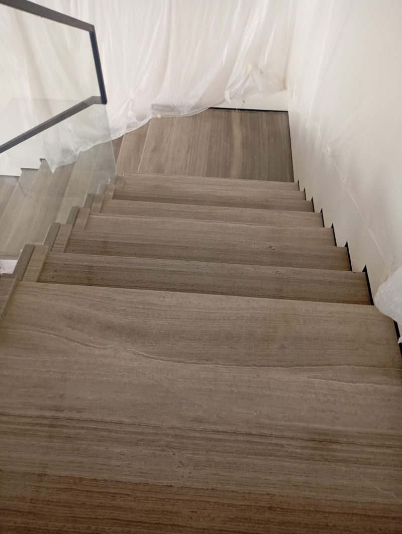 Stone staircase and landing with a glass balustrade under protective sheeting — Reef Al Ghadeer, Al Ain