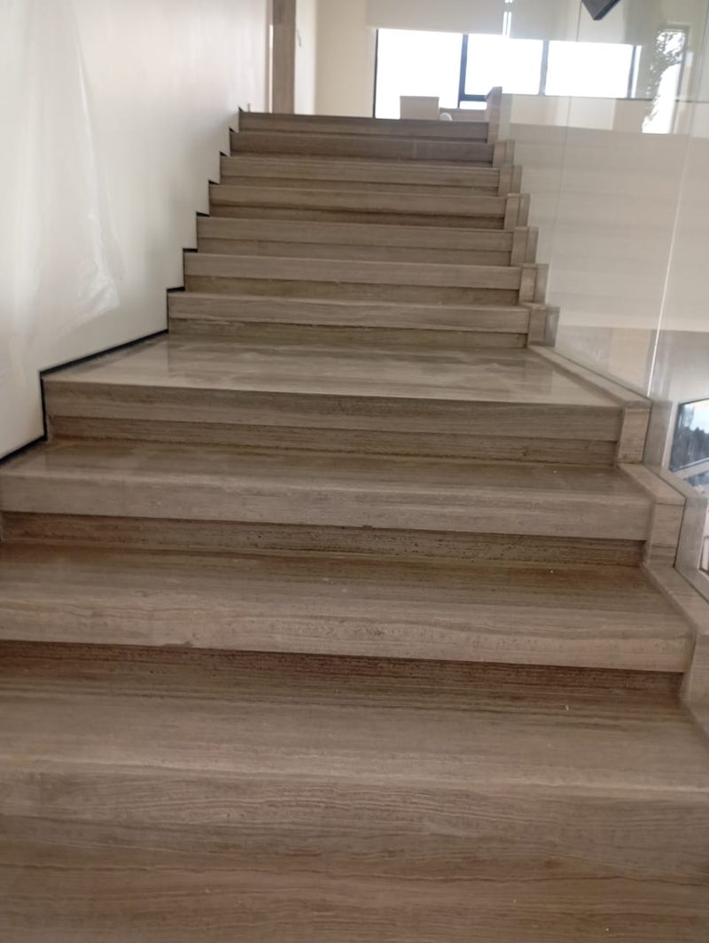 Travertine staircase rising to a landing with a glass balustrade — Reef Al Ghadeer, Al Ain